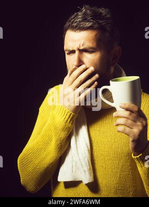Homme barbu malade avec la grippe et la fièvre buvant du thé curatif. Homme malade toussant. Traitement et soins de santé. Beau gars ayant mal à la gorge. L'homme malade est entré Banque D'Images