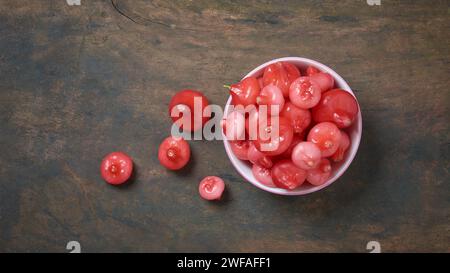 jambu ou pomme rose, aka fruits en cloche ou pomme à cire, la chair est croustillante et aqueuse, tasse pleine de fruits juteux en forme de cloche ou de poire sur la surface de table en bois Banque D'Images