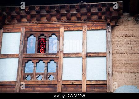 Piments rouges séchant à l'intérieur accrochés à des chevrons vus à travers une fenêtre d'un bâtiment, Bhoutan, Asie Banque D'Images