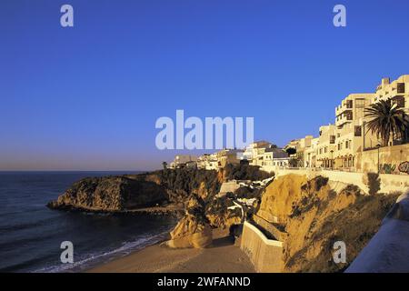 Les appartements, lumineux tôt le matin sous un ciel bleu profond, donnent sur l'extrémité ouest déserte de la plage principale à Albufeira, Algarve, Portugal Banque D'Images