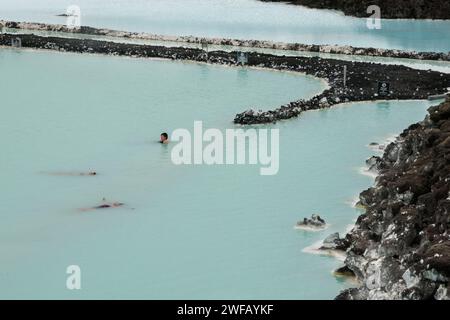 Les touristes flottent dans les eaux minérales chaudes bleu pâle au Blue Lagoon, Islande Banque D'Images