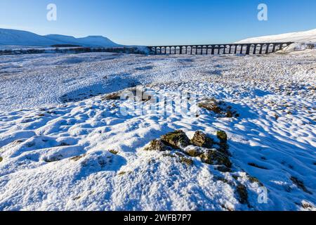 Ingleborough et le viaduc Ribblehead dans les Yorkshire Dales par une journée hivernale avec beaucoup de neige sur le sol et un ciel clair, bleu et sans nuages. Banque D'Images