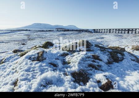 Ingleborough et le viaduc Ribblehead dans les Yorkshire Dales par une journée hivernale avec beaucoup de neige sur le sol et un ciel clair, bleu et sans nuages. Banque D'Images