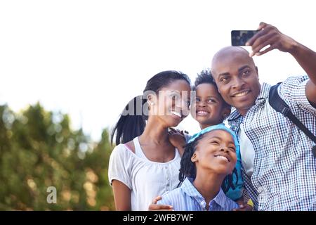 Famille noire heureuse, selfie et photographie dans la nature pour la randonnée, le collage ou la photo en plein air ensemble. La mère africaine, les enfants et le père sourient Banque D'Images