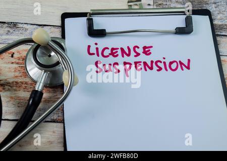 Concept de suspension de licence écrire sur la paperasse avec stéthoscope isolé sur fond en bois. Banque D'Images