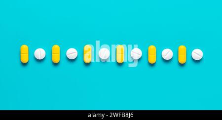 Pilules gros plan sur fond cyan lumineux, vue de dessus, motif créatif abstrait. Ensemble de comprimés médicaux jaunes et blancs. Compléments alimentaires assortis a Banque D'Images