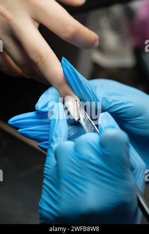 Gros plan d'un pinceau à ongles sculptant de l'acrylique sur un ongle de bord. Banque D'Images