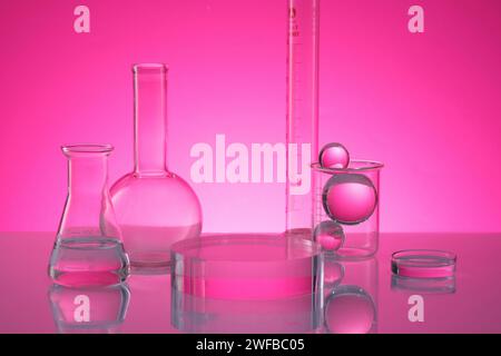 Verrerie de laboratoire telle qu'une boîte de Pétri, un flacon erlenmeyer et un flacon florence à fond plat disposés avec un podium rond sur une table miroir. Science de la recherche Banque D'Images