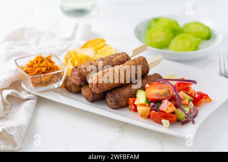 Saucisses traditionnelles du sud de l'europe sans peau cevapcici faites de viande hachée avec des pommes de terre cuites au four et une petite salade et trempette. Banque D'Images