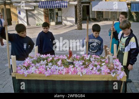 Garçons pratiquant à porter flotteur recouvert de fleurs en plastique avant Pâques Semana Santa célébration, près de la Nouvelle cathédrale à Cadix, Andalousie, Espagne Banque D'Images