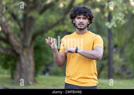 Portrait d'un triste jeune Indien faisant du jogging et du sport dans le parc, insatisfait de son résultat à l'heure de l'émeraude. Il se tient debout, regardant avec déception la caméra et écarte ses mains. Banque D'Images