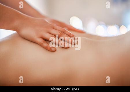 Mains de masseuse appliquant de l'huile sur le dos de l'homme Banque D'Images