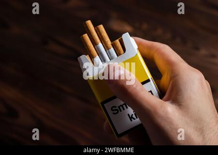 Une main d'homme tenant un paquet ouvert de cigarettes. Banque D'Images