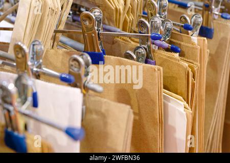 Beaucoup de sacs en papier vides avec des poignées sur un cintre, fond de shopping abstrait Banque D'Images