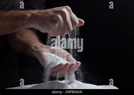 Les mains des hommes gardent le sable dans leurs paumes et répande des grains de sable à travers leurs doigts. Concept du flux de la vie Banque D'Images