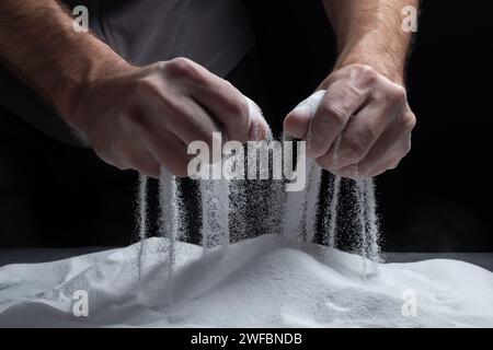 Les mains des hommes gardent le sable dans leurs paumes et répande des grains de sable à travers leurs doigts. Concept du flux de la vie Banque D'Images