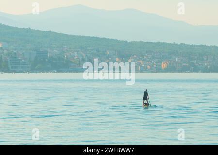 Personne méconnaissable stand-up paddle board à la mer Adriatique Kvarner golfe vu de la côte de la ville de Crikvenica, mise au point sélective Banque D'Images