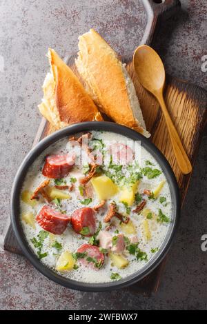 Zalewajka est une soupe polonaise traditionnelle à base de soupe de blé entier, saucisse fumée, bacon fumé aromatique et légumes-racines gros plan sur le pl Banque D'Images