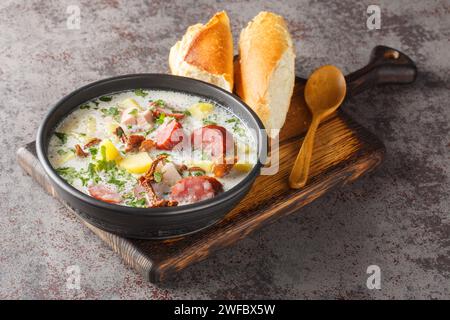 Zalewajka traditionnel levain de seigle et soupe de pommes de terre avec saucisse et champignons séchés gros plan sur l'assiette sur la table. Horizontal Banque D'Images