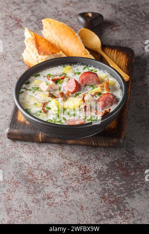 Borscht blanc polonais avec légumes, saucisse fumée, champignons séchés et bacon gros plan dans une assiette sur la table. Vertical Banque D'Images