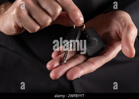 Main masculine tenant la clé de voiture, sur fond sombre. Banque D'Images