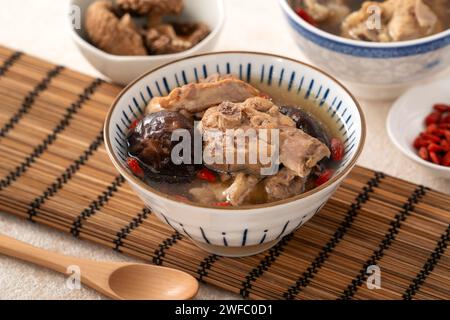 Délicieuse soupe de poulet aux champignons shiitake take taïwanais dans un bol sur fond de table blanc. Banque D'Images