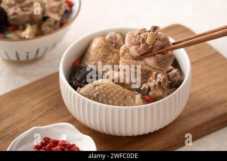 Délicieuse soupe de poulet aux champignons shiitake take taïwanais dans un bol sur fond de table blanc. Banque D'Images