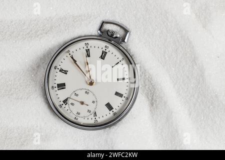 Vieille belle montre de poche couchée dans le sable de plage. Banque D'Images