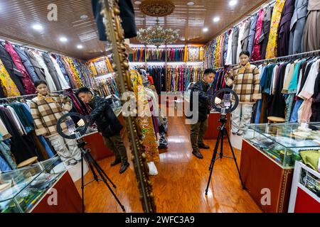 (240130) -- CHENGDU, 30 janv. 2024 (Xinhua) -- Nyima Wangden (à gauche) et sa fille vendent des costumes tibétains traditionnels par diffusion en direct dans leur magasin de vêtements à Chengdu, dans la province du Sichuan, dans le sud-ouest de la Chine, le 5 janvier 2024. Nyima Wangden, un homme d'affaires tibétain originaire du comté de Heishui dans l'Aba Tibetan et de la préfecture autonome de Qiang dans le Sichuan, vit à Chengdu, la capitale provinciale, depuis plus de deux décennies. Nyima Wangden et son épouse Hoing Je, qui avaient tous deux hérité de leurs aînés de l’artisanat de la conception et de la fabrication de costumes tibétains traditionnels, ont exploité un vêtement spécialisé Banque D'Images