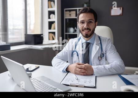 Docteur masculin au bureau souriant à la caméra Banque D'Images