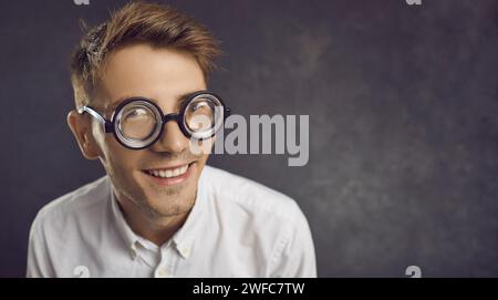 Gros plan portrait de nerd souriant drôle dans des lunettes rondes sur fond d'espace de copie Banque D'Images