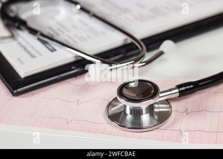 Stéthoscope sur papier ECG d'électrocardiogramme. Acquisition ECG du diagramme cardiaque isolé sur blanc. Assurance santé et formation médicale Banque D'Images