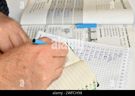 L'image montre une main d'homme, dans laquelle il tient un stylo plume et écrit quelque chose. Banque D'Images