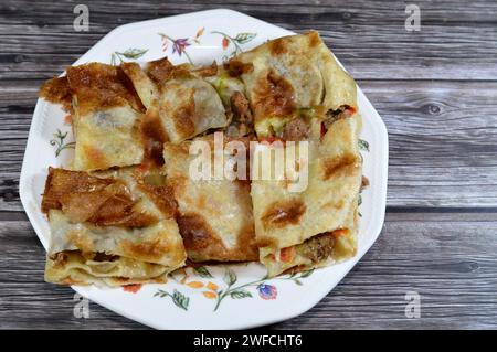 Tarte à la saucisse de viande du Moyen-Orient cuite au four et tranchée en morceaux, avec des morceaux de saucisse de bœuf, de viande hachée, de tomates, de poivrons, d'herbes et d'épices Banque D'Images