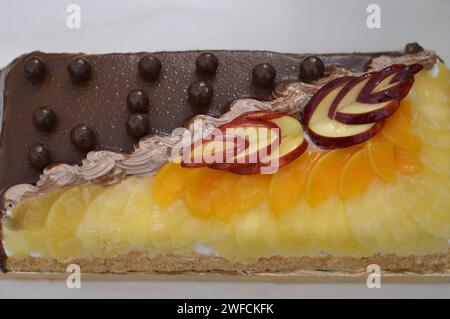 Gâteau d'anniversaire de deux moitiés différentes pièces gâteau crémeux spongieux pour les célébrations, chocolat noir, caramel, crème fouettée à la vanille, tranches d'ananas Banque D'Images