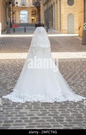 Vue arrière mariée musulmane dans sa robe de mariée blanche debout à l'extérieur Banque D'Images