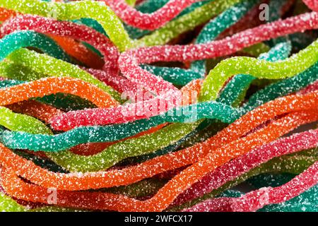 Bonbons gélifiés multicolores en forme de spaghetti saupoudrés de sucre. Gros plan. Banque D'Images