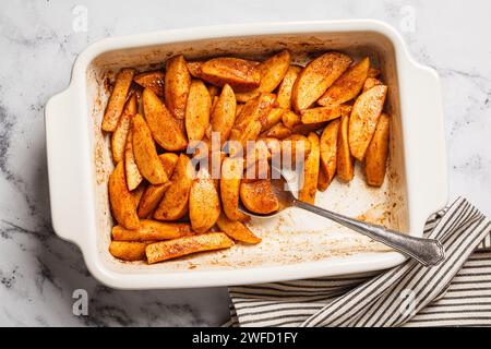 Tranches de pommes cuites au four avec cannelle et sirop d'érable dans une poêle blanche, vue de dessus. Banque D'Images