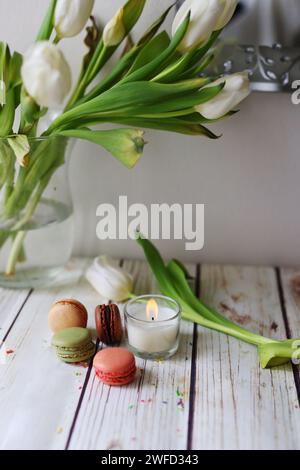 Nature morte romantique avec une bougie, des macarons et des tulipes Banque D'Images