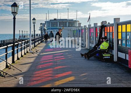 Les gens profitant d'une promenade sur la jetée Worthing par une journée d'hiver ensoleillée et froide, West Sussex Angleterre Royaume-Uni Banque D'Images