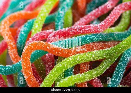 Bonbons gélifiés multicolores en forme de spaghetti saupoudrés de sucre. Gros plan. Banque D'Images