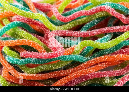 Bonbons gélifiés multicolores en forme de spaghetti saupoudrés de sucre. Gros plan. Banque D'Images