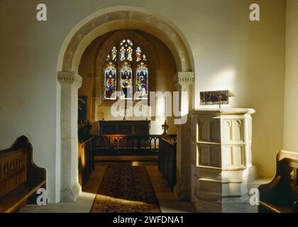 Vue intérieure à l'E de St Andrew's Church, Coln Rogers, Gloucestershire, Angleterre, Royaume-Uni, montrant la chaire de pierre C15ème à côté de l'arc de choeur saxon Banque D'Images