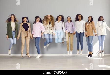 Groupe de femmes d'affaires heureuses regardant la caméra, se tenant la main et sautant. Banque D'Images