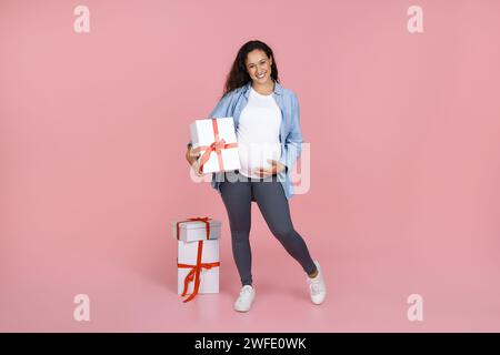 Belle jeune femme enceinte posant avec des boîtes cadeaux emballées Banque D'Images