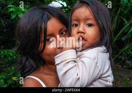 Une fille prend soin de sa sœur pendant que ses parents travaillent, famille locale dans le village riverain de Timicuro I. Iqutios amazonie péruvienne, Loreto, Pérou Banque D'Images