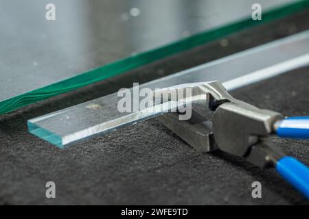 Atelier de verre, Un morceau de verre épais couché sur la table, cassé à l'aide d'un brise-verre spécialisé. Travailler dans une usine de verre Banque D'Images