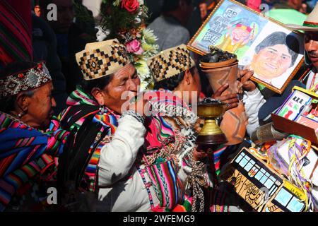 La Paz, BOLIVIE ; 24 janvier 2015. Une chamane mâchant des feuilles de coca se tient à côté d’un homme tenant une photo du président bolivien Evo Morales lors d’un événement marquant le début du festival Alasitas à la Paz. Le dessin a été donné à Evo Morales en cadeau après la prise de ces images. Banque D'Images