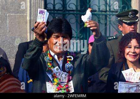 La Paz, BOLIVIE ; 24 janvier 2015. Le président bolivien Evo Morales tient une liasse de billets miniatures et une poule (un cadeau des artésiens) lors d’un événement marquant le début du festival Alasitas à la Paz. Au festival, les gens achètent des miniatures de ce qu'ils veulent obtenir au cours de l'année et les font bénir pour que leurs souhaits deviennent réalité. Les poules sont souvent achetées par ou données à des personnes célibataires qui pensent être à la recherche d'un partenaire.. ! Banque D'Images