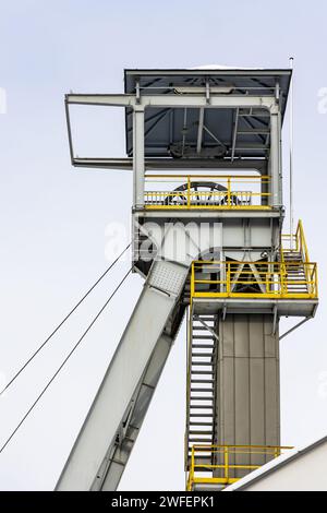 Un arbre de palan de mine contre un ciel gris. Gros plan des roues en haut de l'arbre. Banque D'Images